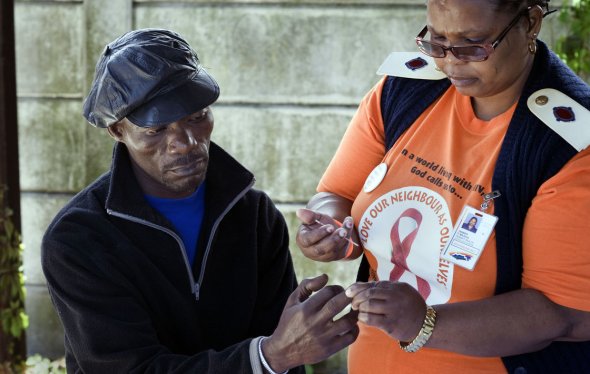 At a roadside HIV-testing table near Cape Town, South Africa, a nurse tests a man's blood_2012_photograph by Rodger Bosch_While South Africa has the highest percentage worldwide of people living with HIV – about 6 million in a nation of 53 million – it also has the world's largest treatment programme using Anti-Retroviral drugs distributed from several thousand  health clinics. 