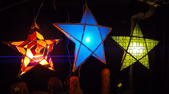 The Parol or Paritaán, is the Christmas lantern of the Philippines.  Often constructed of bamboo and paper, it is now made of many materials.  Originally candle-lit, electric lights – bulbs or LED in a garland – are used now in a variety of colours.  The Parol's design is star-shaped – meant to evoke the Star of Bethlehem that guided the Three Wise Men/Kings to the Christ-Child's Manger.  The Parol also symbolizes hope and goodwill / the victory of light over darkness. These three Parols were made by Kat Estacio, Caroline Mangosing and Katrina Estacio at the Kapisanan Community Centre, Toronto, Canada.