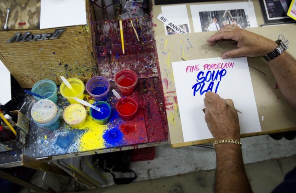 Honest Ed's signpainter, Wayne Reuben, at work in July 2013_photograph by Darren Calabrese, National Post